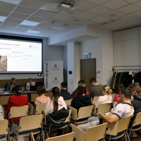 Powiększ obraz: grupa studentów siedzi przed wykładowcami