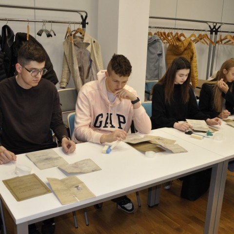 Powiększ obraz: studzenci siedzą przy stołach w sali konferencyjnej, na stołach materiały do konserwacji akt