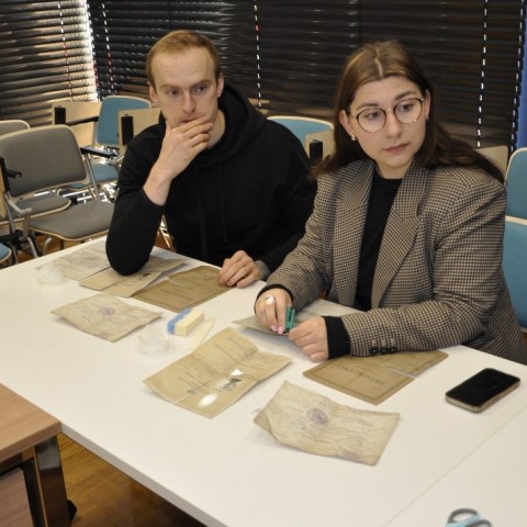 Powiększ obraz: studzenci siedzą przy stołach w sali konferencyjnej, na stołach materiały do konserwacji akt